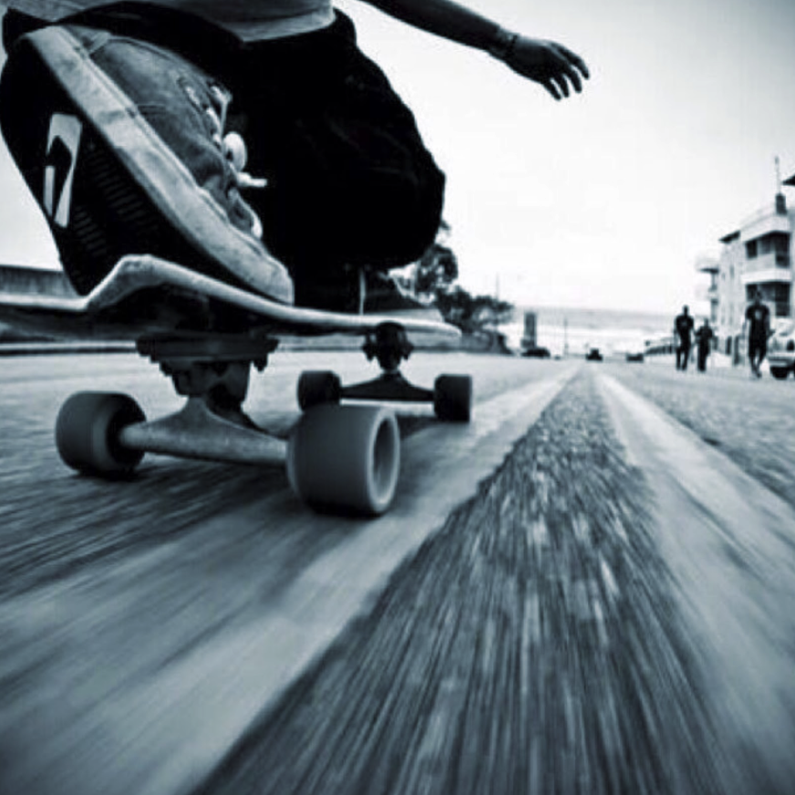 ground level angle of a skateboarder on a skateboard on a road riding towards a beach