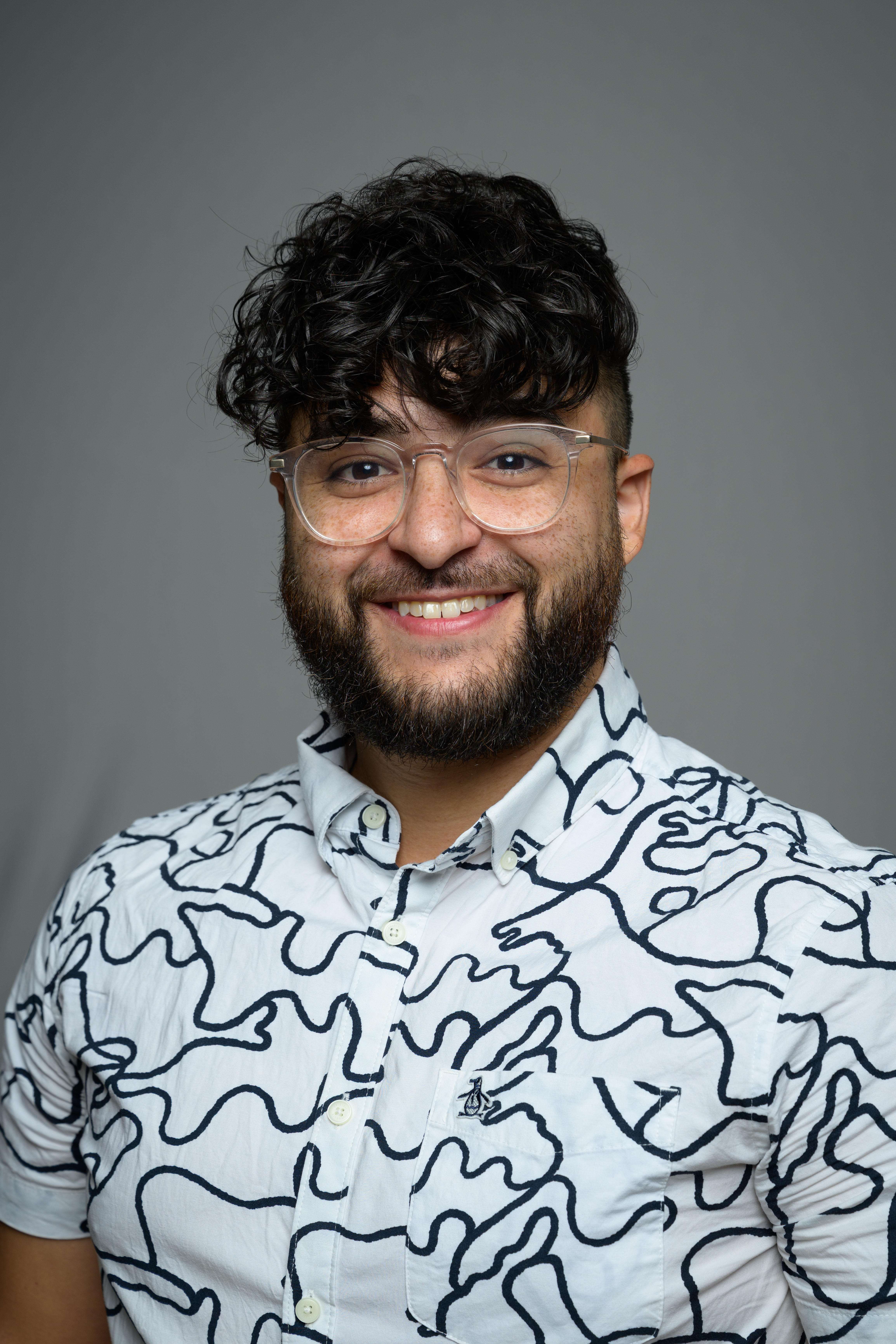 Domenic smiling in a white and black shirt and glasses