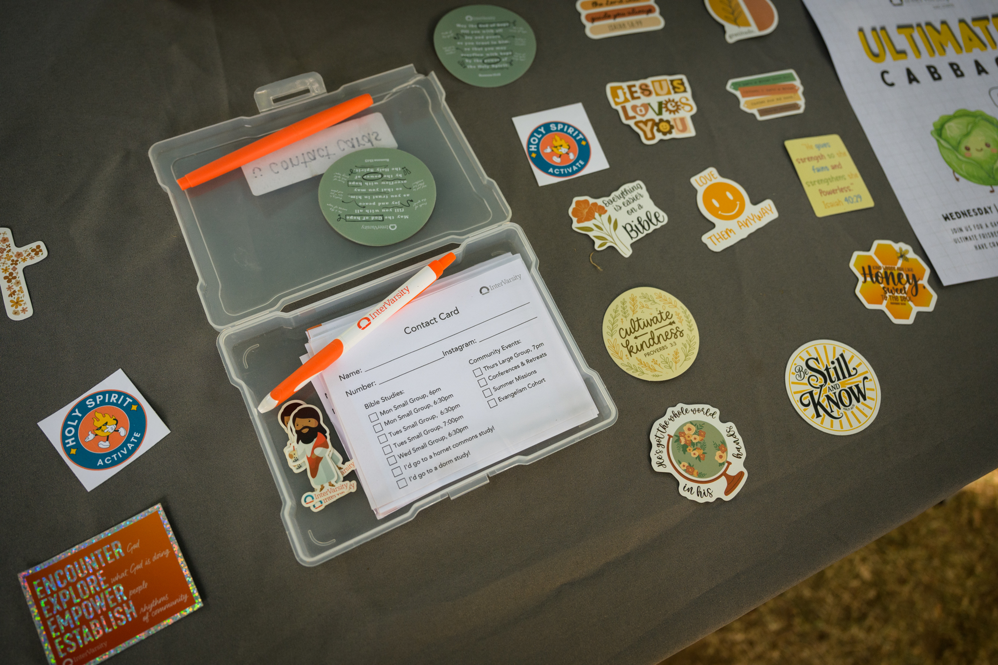 A box of contact cards sits ready to be filled out by new people, surrounded by various fun stickers free for the taking.