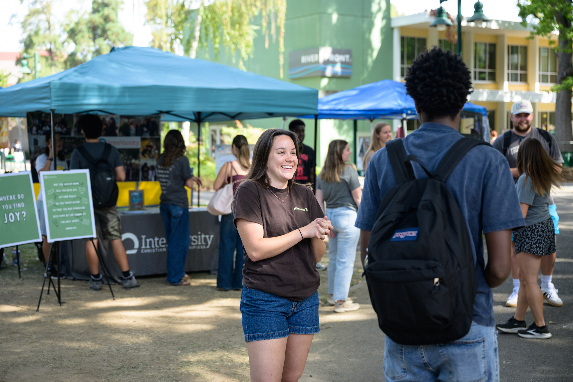 Ashlyn, a student leader, has a conversation with a student that was passing by the table, wearing a ready smile to welcome him.