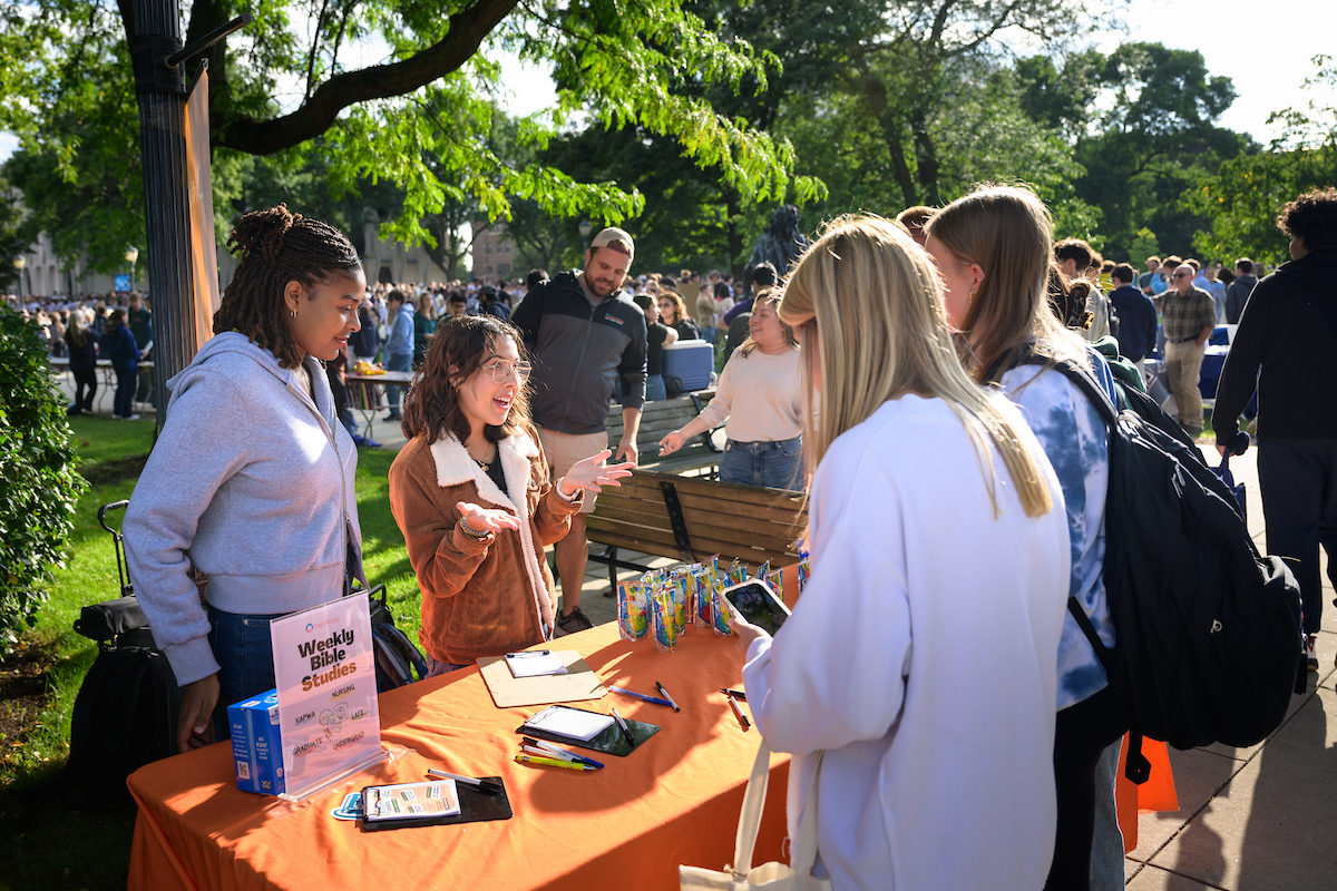 students talking to other students at a table