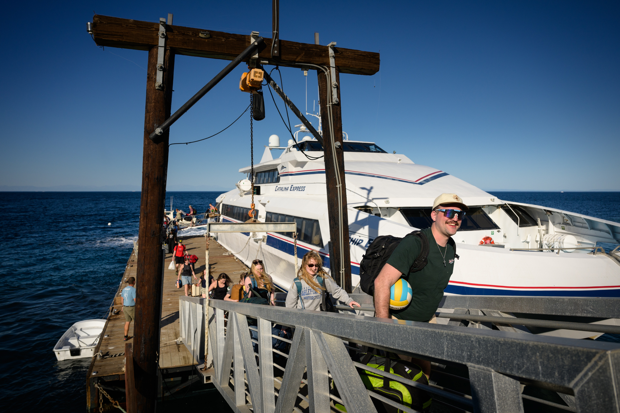students and staff arriving by boat to catalina island walking up the dock carrying their luggage