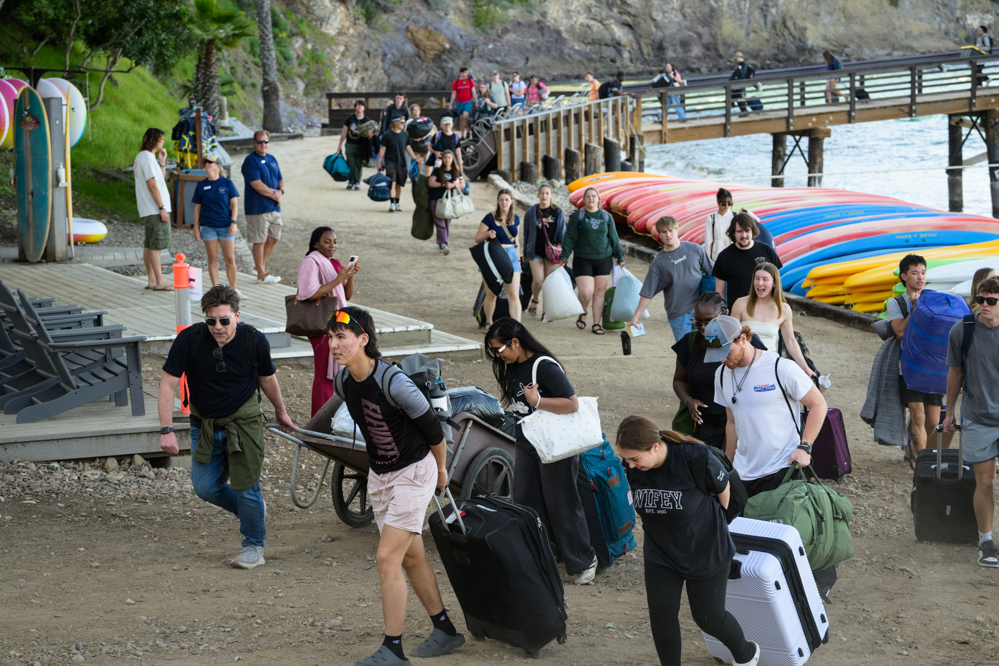 students and staff carrying their luggage up the rocky path up the hill to get to their cabins