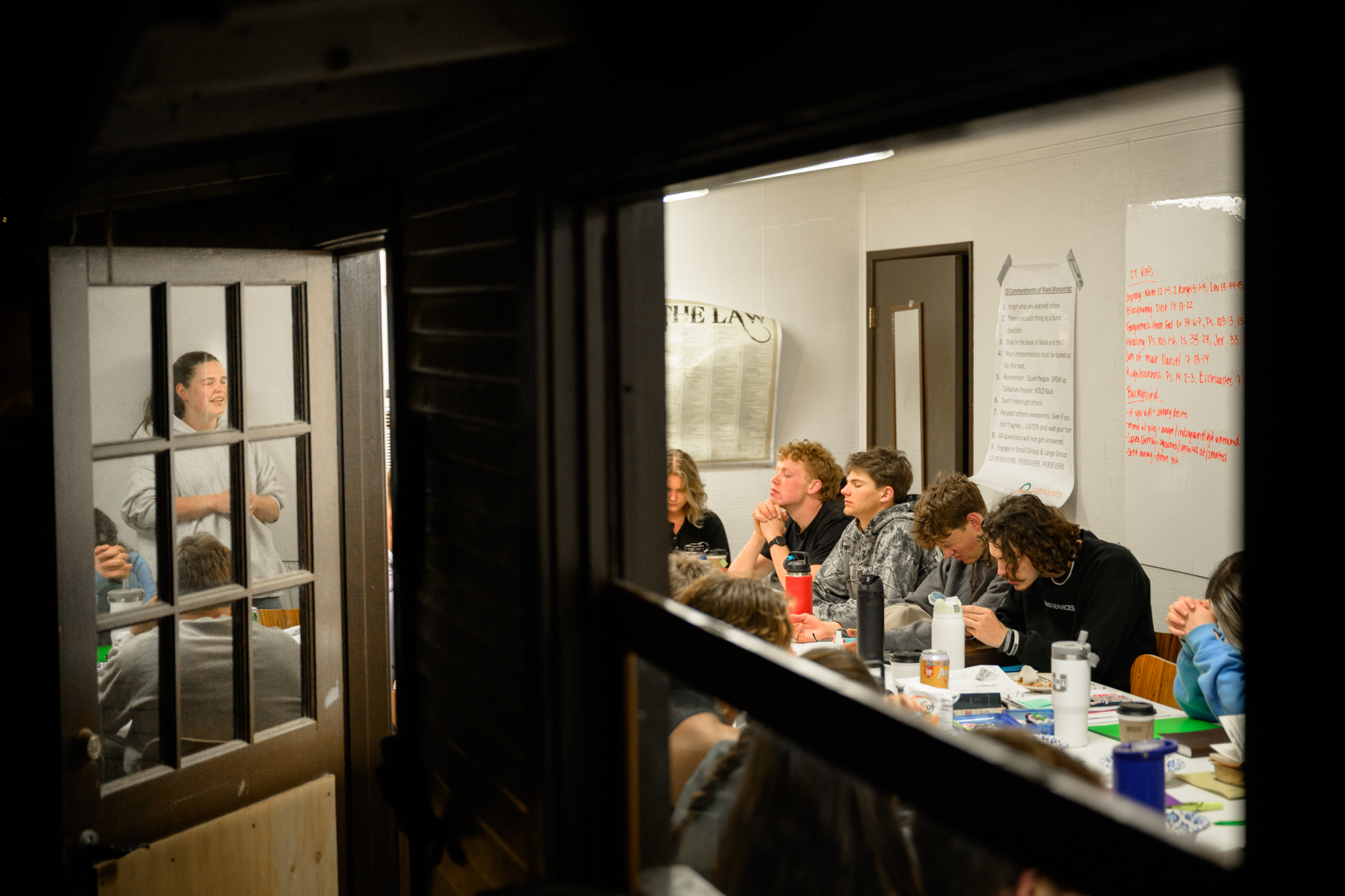 Camera looks through the window as students pray before chapter time