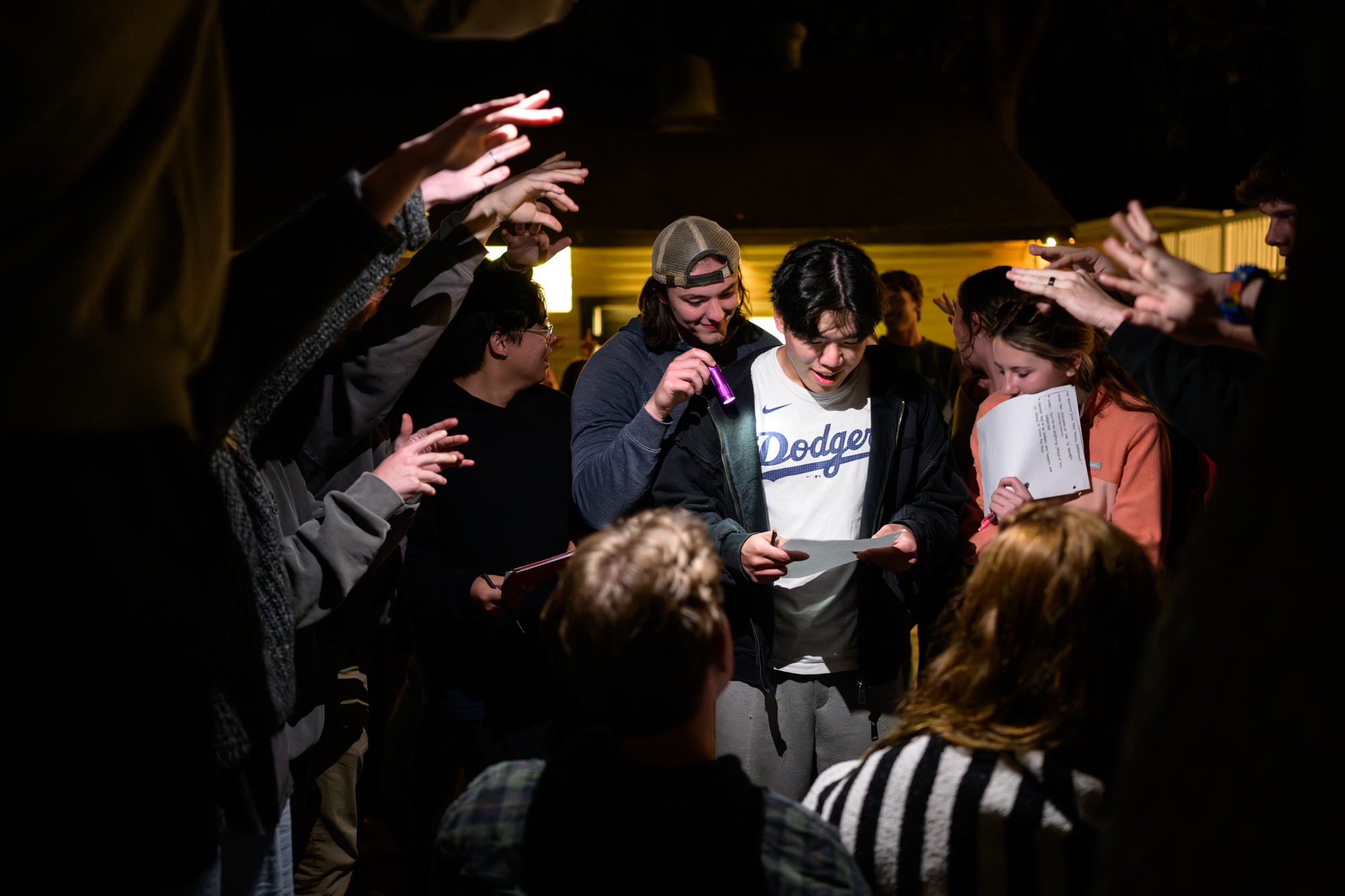 Students hold flashlights to illuminate the manuscript passage as they try to answer a question from the staff.