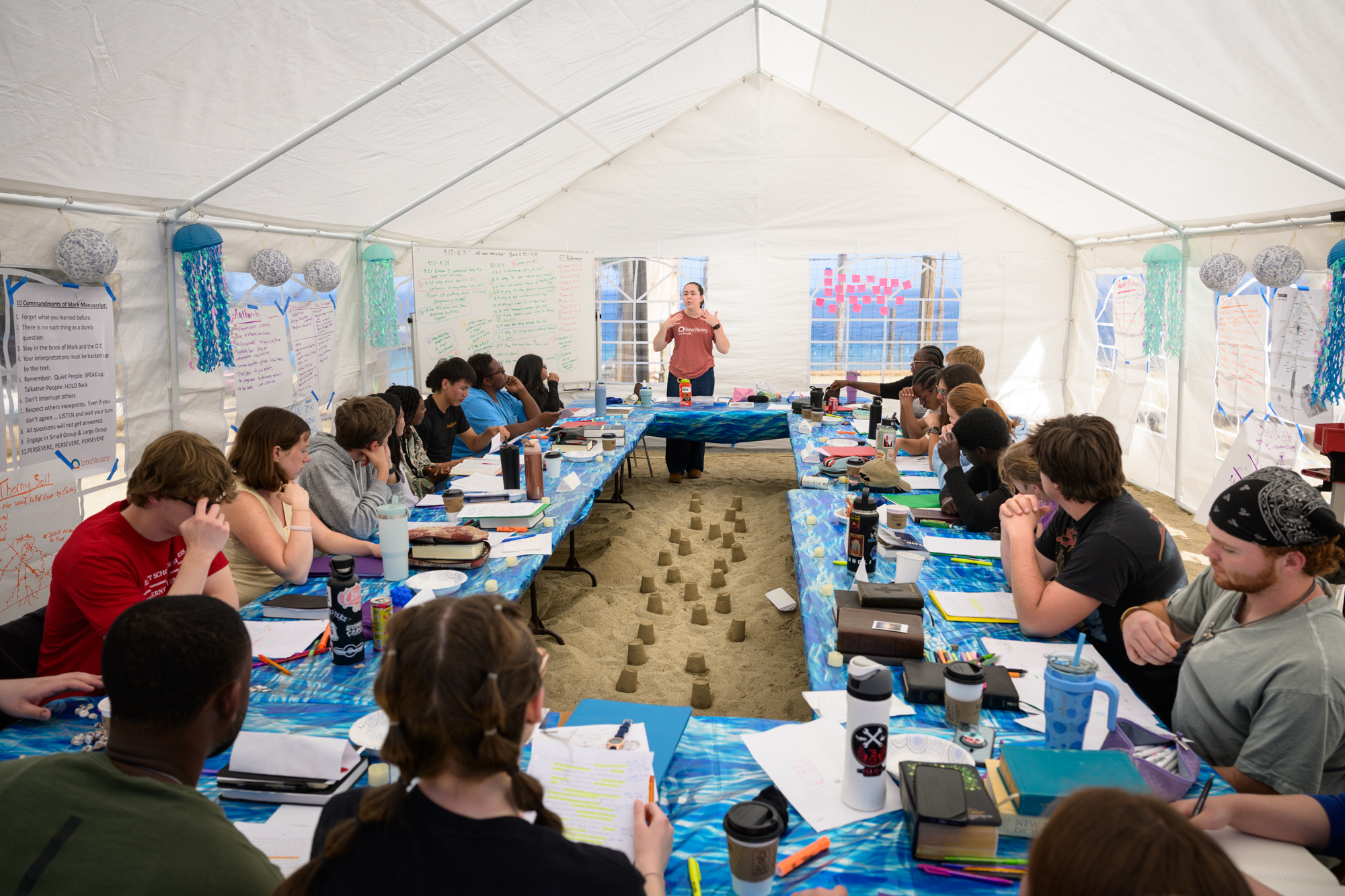 staff leading track time in a big white tent set up on the volleyball court because they ran out of room - students built little sandcastles in the sand between the tables as well