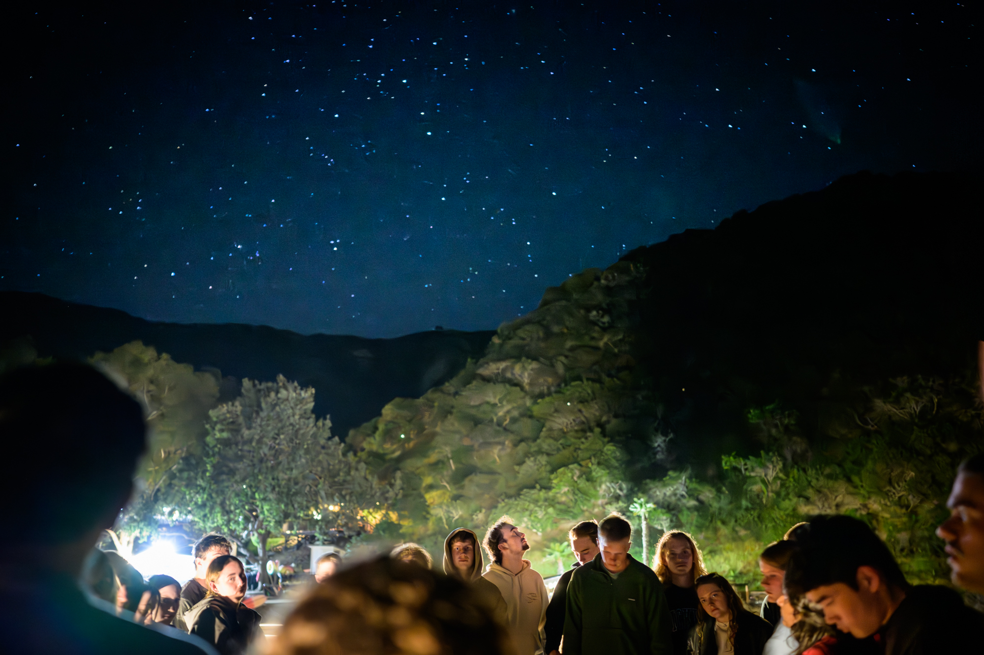 Students worship on the dock outside under the star filled night sky. One student looks up at the sky.