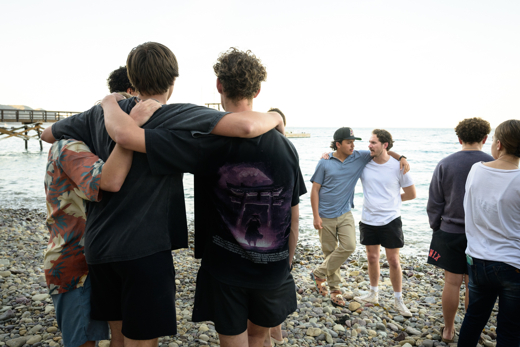 Students embracing with arms around shoulders talking and reflexing on the week while looking out to the ocean