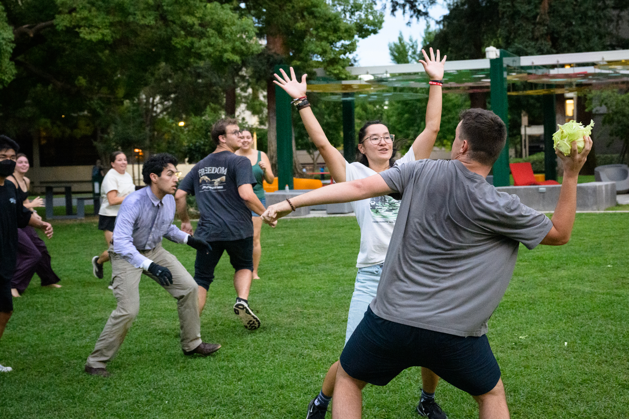 A student winds up to throw a head of cabbage down a field as others raise their hands to block the throw.