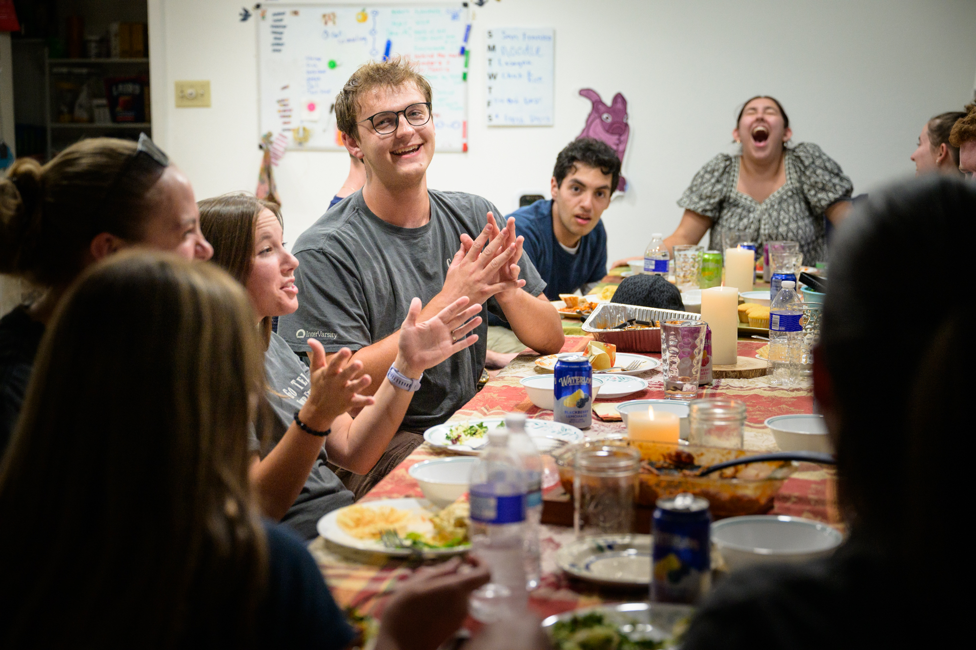 A student smiles at his own embarrassing story as everyone around him laughs.