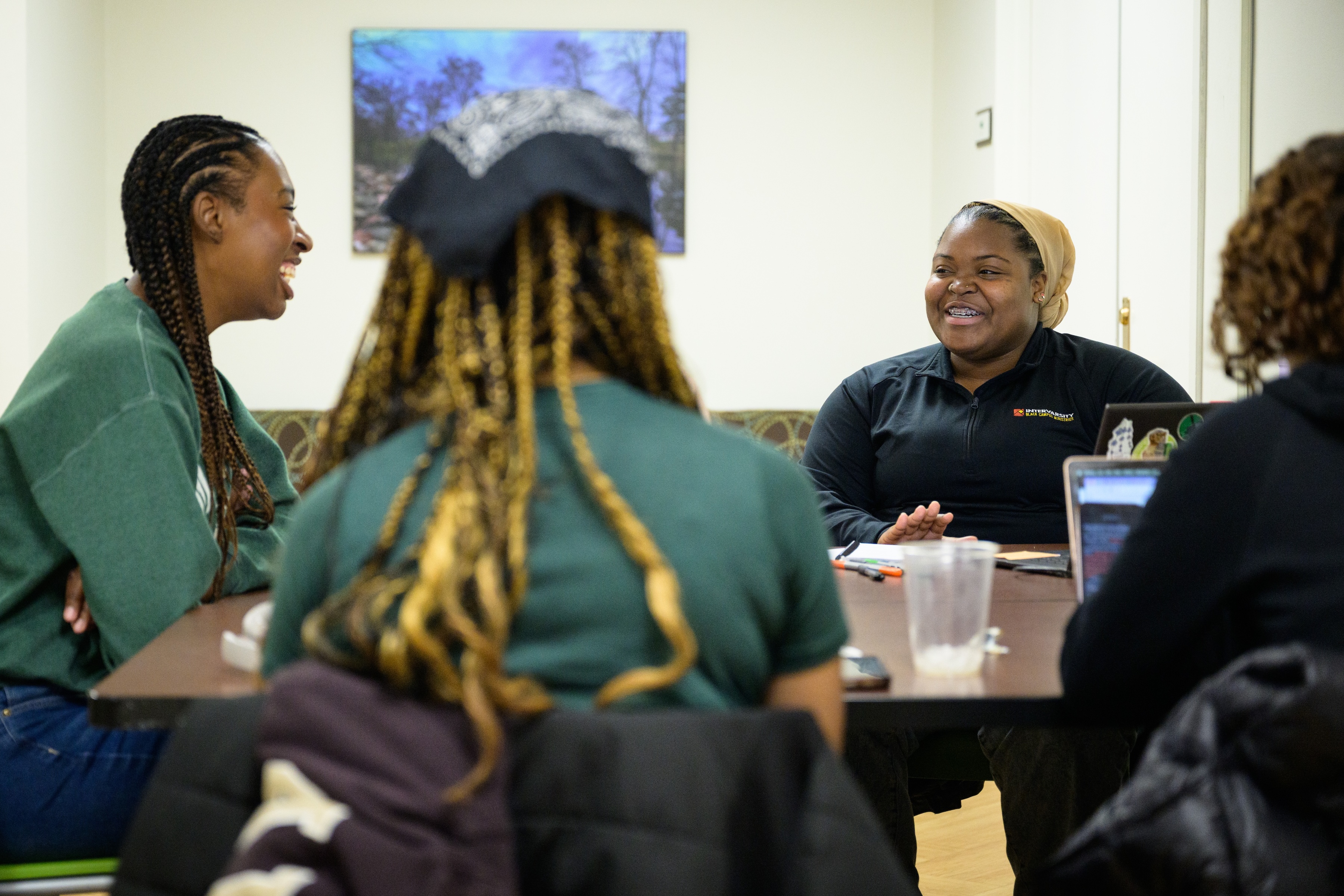 4 female BCM students sitting around a table laughing and talking 