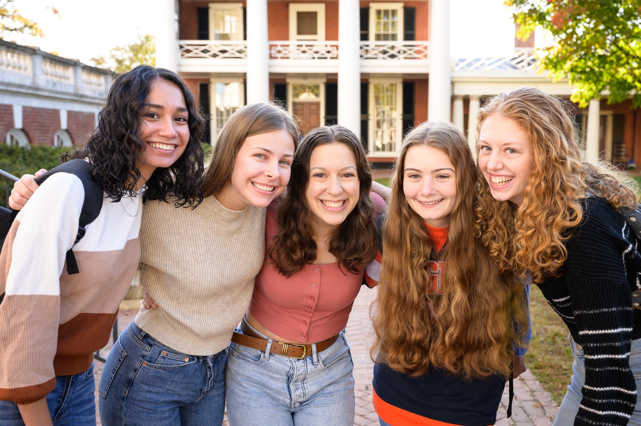 5 female students smiling with their arms around each other