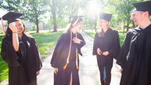 Group of students laughing, wearing caps and gowns