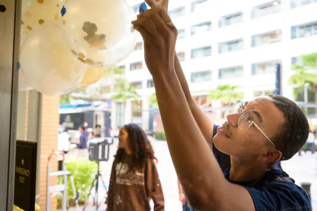 male student hanging balloon