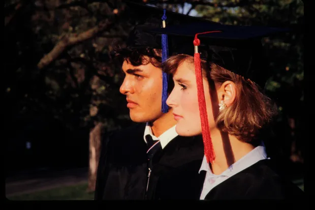 side view of two students in graduation caps