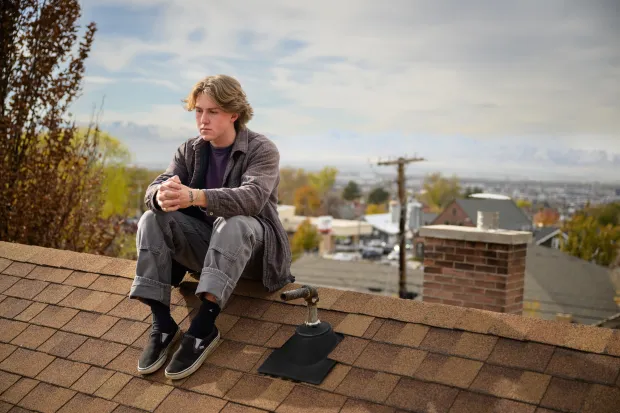 photo of male student sitting on roof