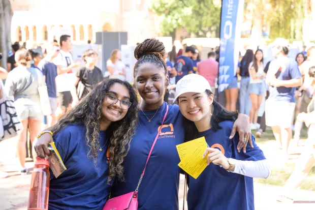 3 smiling female students and a yellow contact card