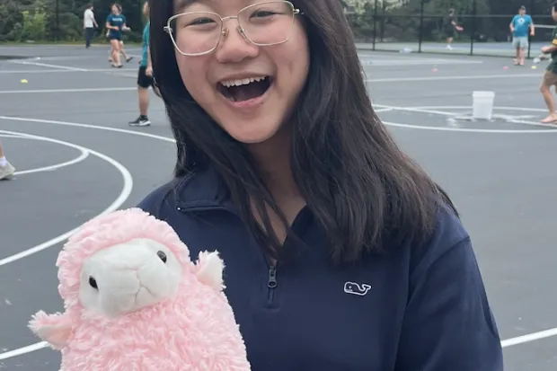 Sam smiling and holding stuffed lamb toy named Gerald (the unofficial InterVarsity mascot).