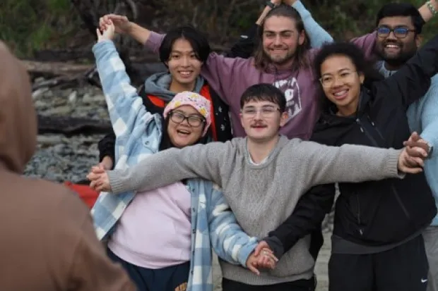 diverse group photo of people making a star shape with their arms and hands linked