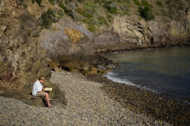 student reading and praying by water