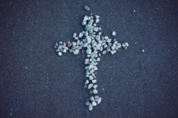 A white and gray cross formed out of small pebbles