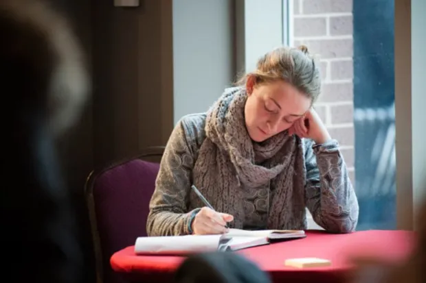 a woman seated at a round table and journaling