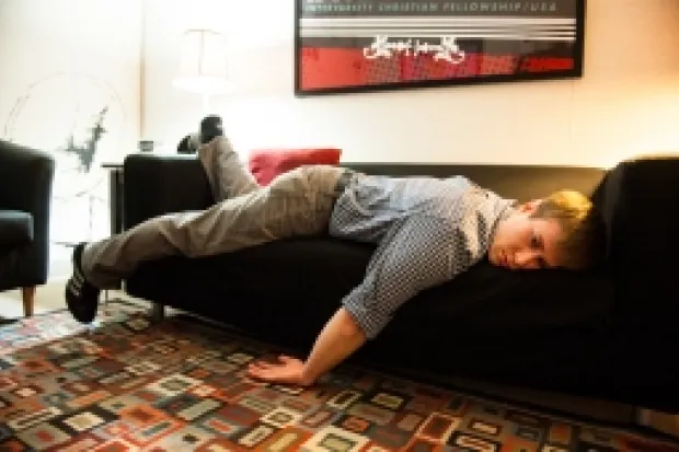 Young man in office clothes sprawled across couch