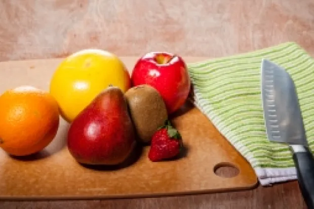 a wooden table with fruits, vegetables, and knife