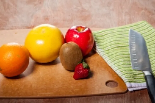 a wooden table with fruits, vegetables, and knife