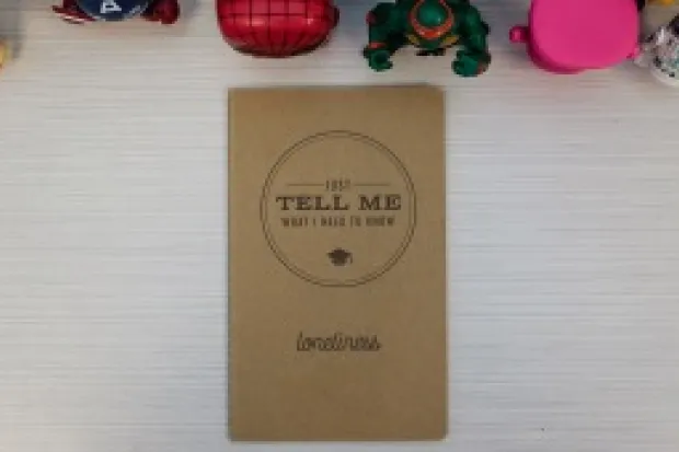 a small canvas notebook with "Just Tell Me What I Need to Know" on its cover