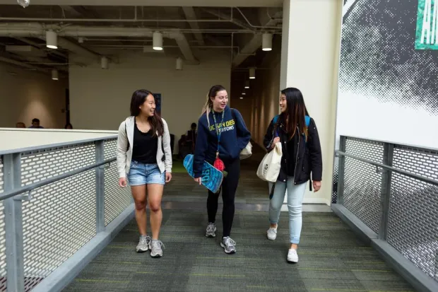 Three students talking and laughing as they walk to class