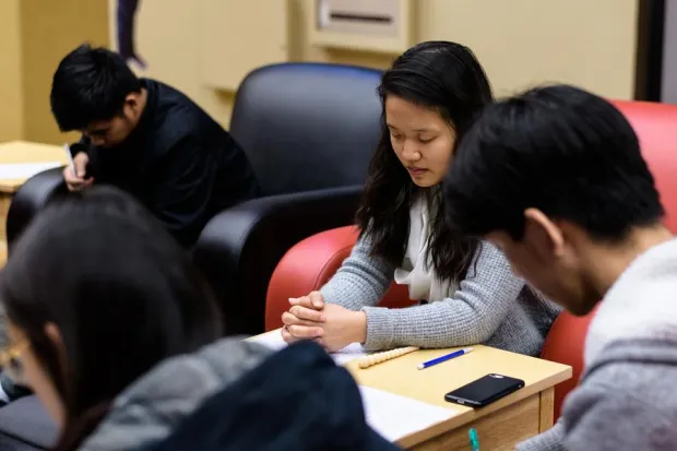 Group of Asian American students praying during Bible study