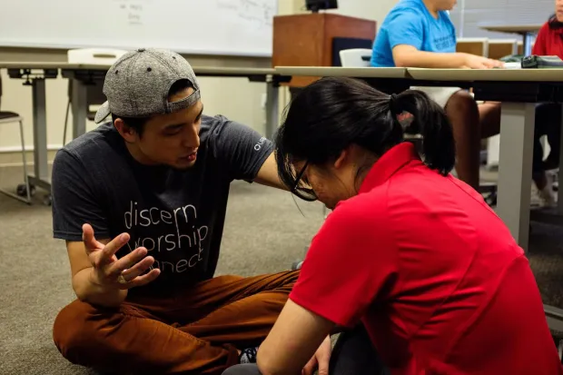 Campus minister praying for student in classroom