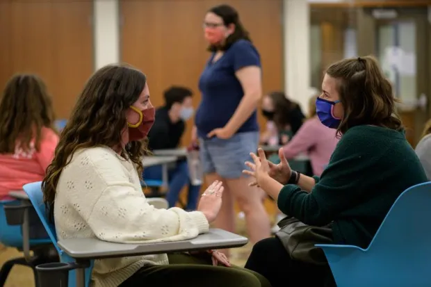 Two students talking during large group meeting