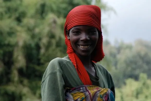 Young African woman smiling wearing red headwrap and green dress