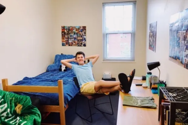 Student sitting with legs propped up on desk in freshmen dorm room