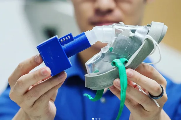 A person holding a medical mask with an air filter attached.