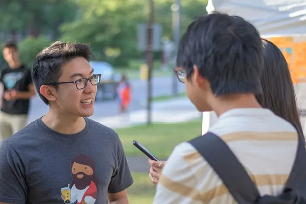 Stephan on campus talking with two students outside