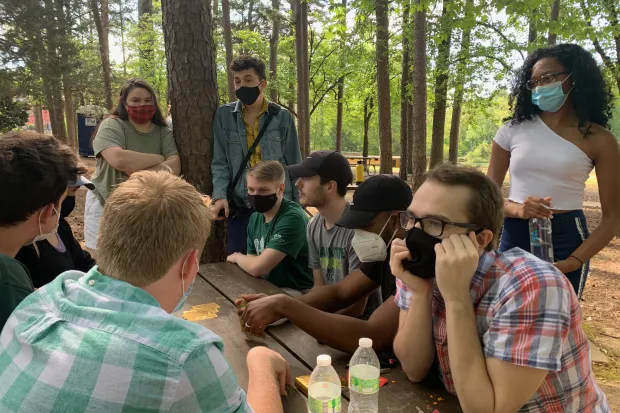 Calvin with group of fellow InterVarsity students seated at picnic table surrounded by trees