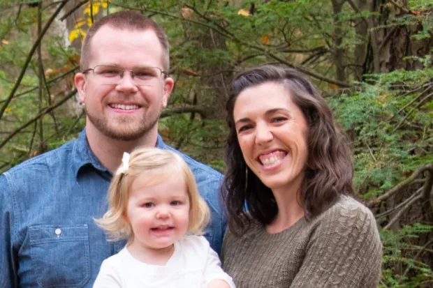 Photo of Ryan with wife and infant daughter standing in forest