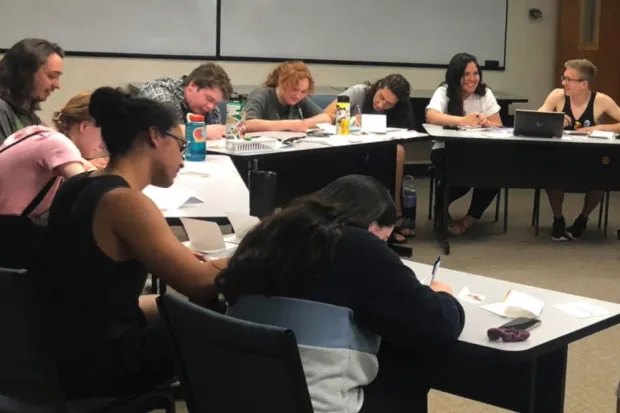 Group of students seated at tables writing letters to incoming freshmen