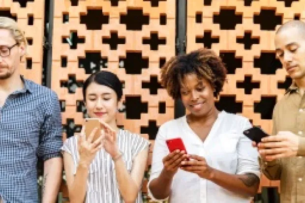 Group of people all staring at smartphones standing side by side