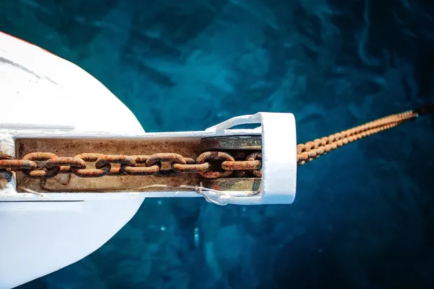 Looking down on a boat anchor lowered into the water