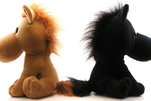 two stuffed horse dolls, one brown and the other black, facing in opposite directions