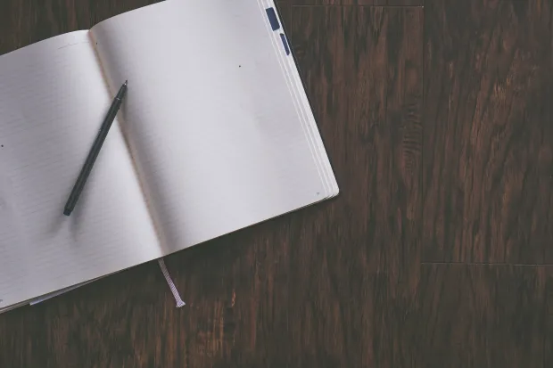 a blank notebook and pen resting on a table