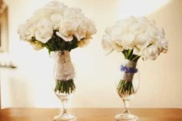 Two bouquets of white roses in glass vases on table