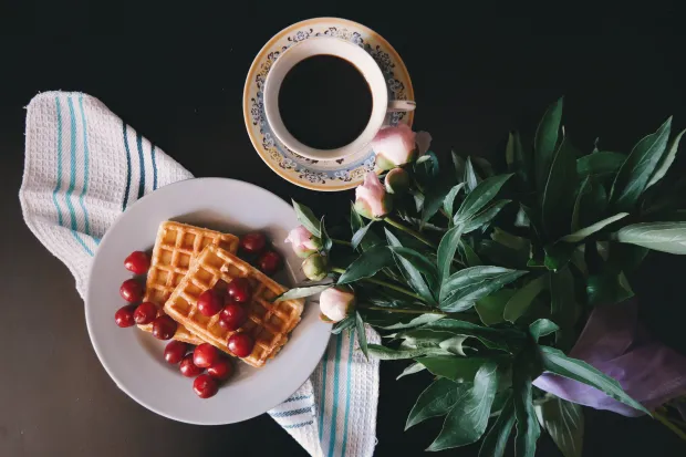 Plate of waffles with coffee on table next to plant