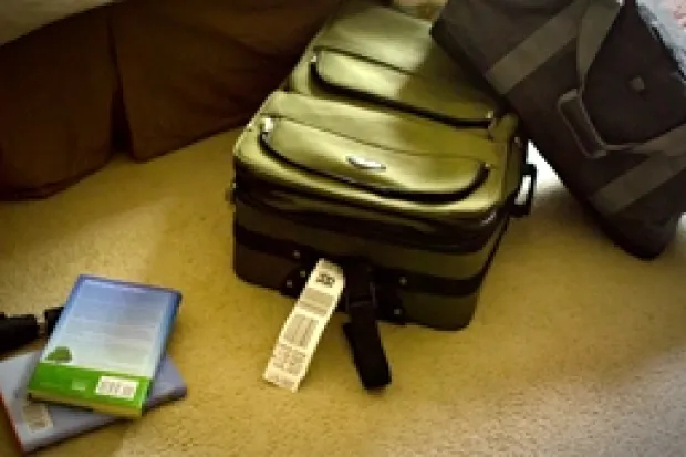 Luggage tipped over on the floor next to couch and stack of books