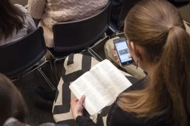 a woman holding an open Bible in her lap at church