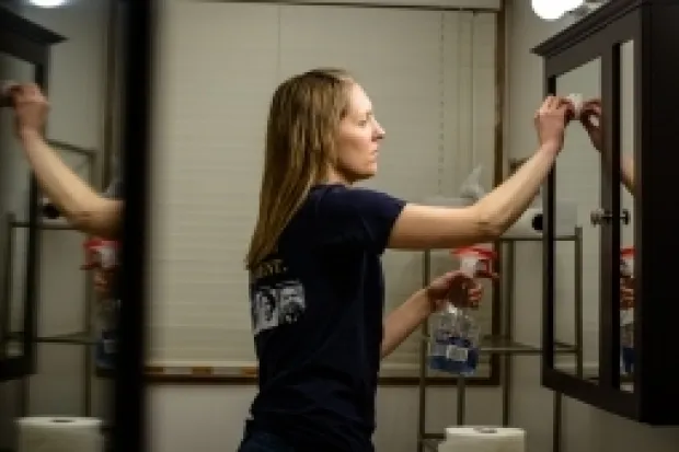 Woman cleaning bathroom mirror